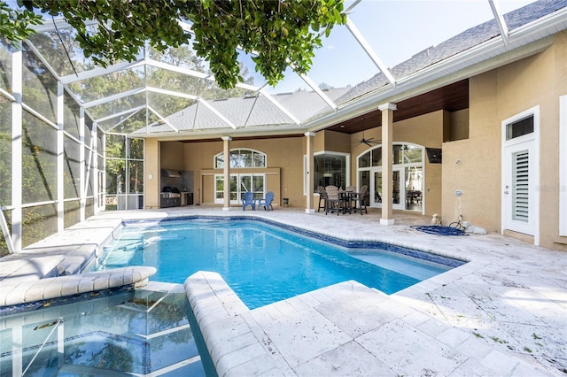 view of pool featuring glass enclosure, ceiling fan, a patio, and an in ground hot tub