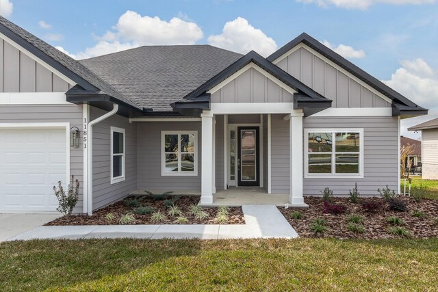 view of front of house featuring covered porch, a garage, and a front lawn