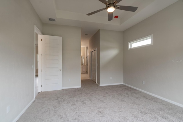 unfurnished room with light colored carpet, a raised ceiling, and ceiling fan