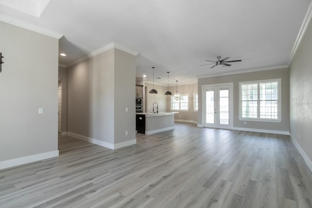 11828 NW 15th Rd, Gainesville, FL 32606 - unfurnished living room featuring light wood-style flooring, ceiling fan with notable chandelier, a sink, and baseboards