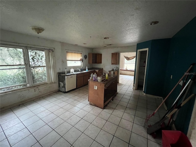 kitchen with kitchen peninsula, dishwasher, light tile patterned flooring, and a textured ceiling