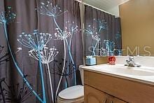 bathroom with a shower with curtain, vanity, and toilet