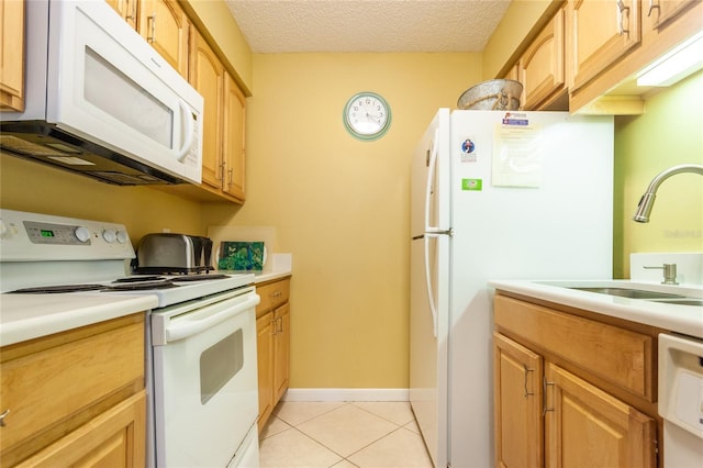 kitchen with light tile patterned flooring, a textured ceiling, white appliances, and sink