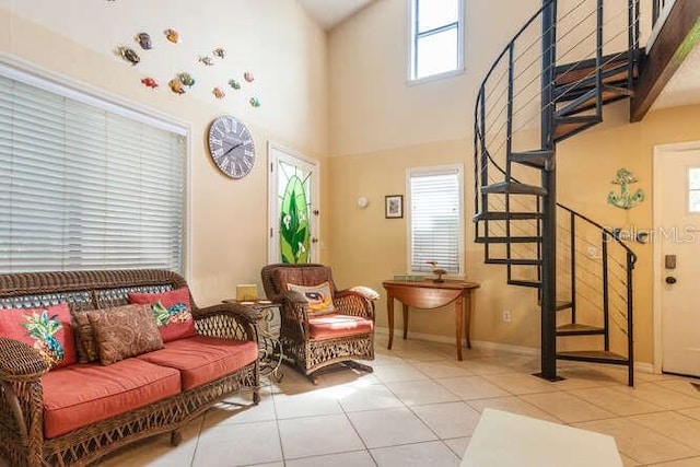 living area with a high ceiling, plenty of natural light, and light tile patterned flooring