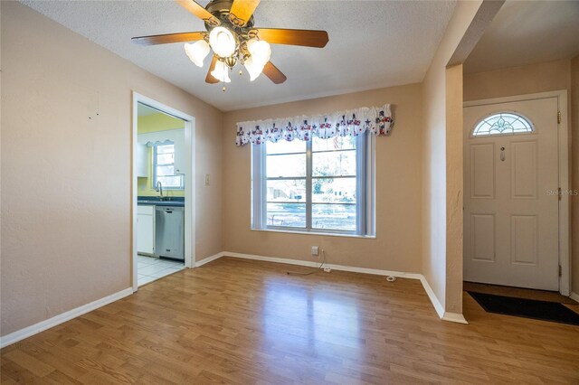 foyer entrance with a textured ceiling, light hardwood / wood-style flooring, ceiling fan, and sink