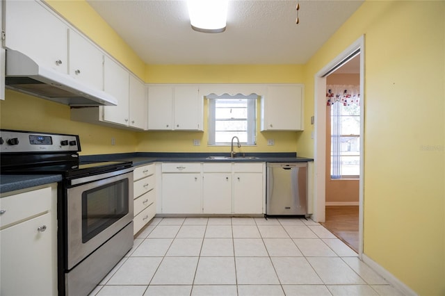 kitchen with sink, white cabinets, light tile patterned floors, and appliances with stainless steel finishes