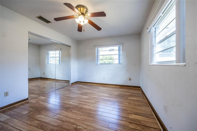 empty room with ceiling fan, hardwood / wood-style floors, and plenty of natural light