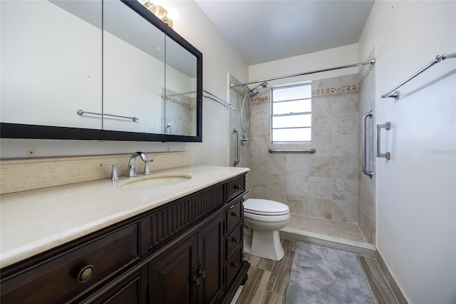 bathroom with vanity, toilet, and a tile shower