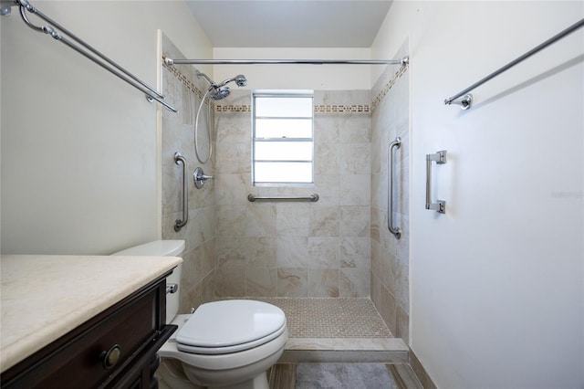 bathroom featuring tiled shower, vanity, and toilet