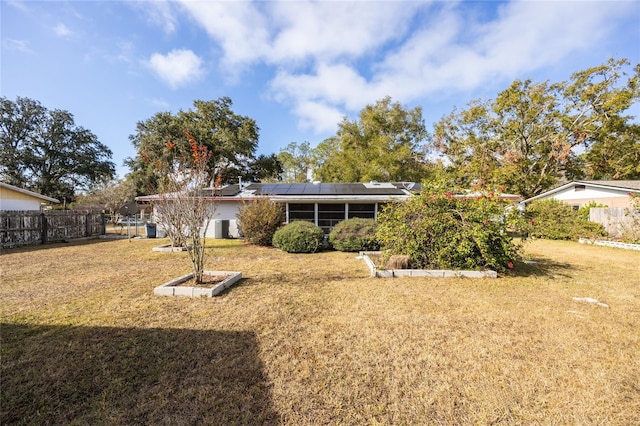 back of house with solar panels, a yard, and central air condition unit