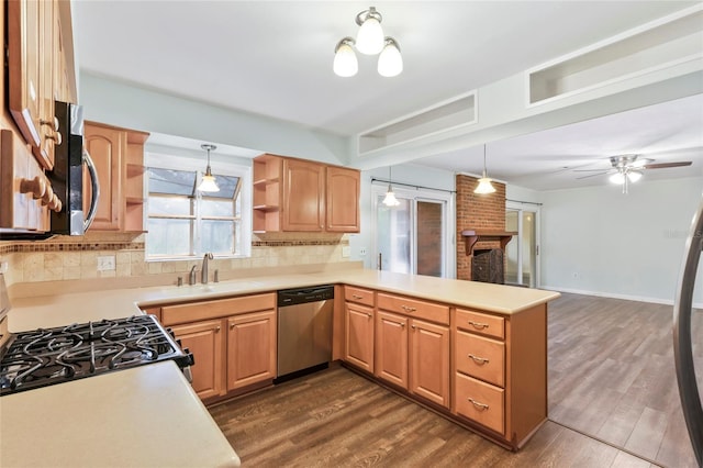 kitchen featuring pendant lighting, sink, stainless steel dishwasher, gas range oven, and kitchen peninsula