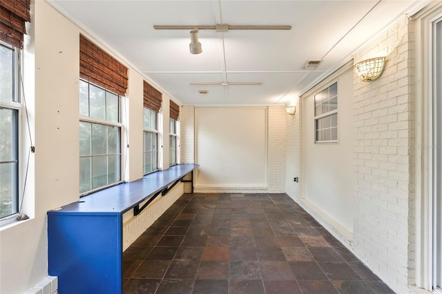 mudroom featuring a healthy amount of sunlight and brick wall