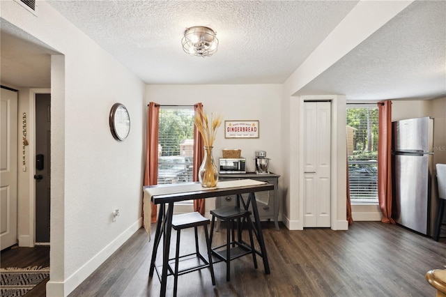 dining area with dark hardwood / wood-style floors, a healthy amount of sunlight, and a textured ceiling