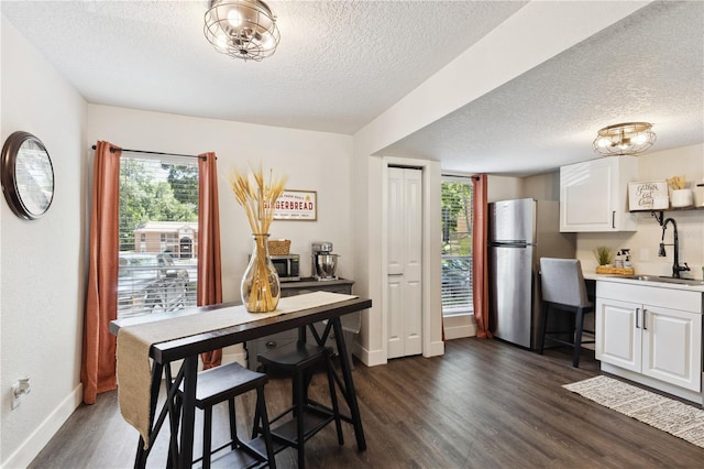 dining space with a textured ceiling, dark hardwood / wood-style floors, and sink