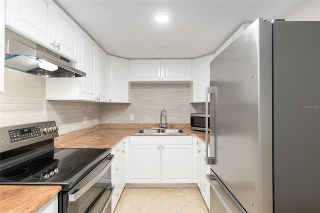 kitchen featuring sink, light tile patterned flooring, white cabinetry, appliances with stainless steel finishes, and butcher block counters