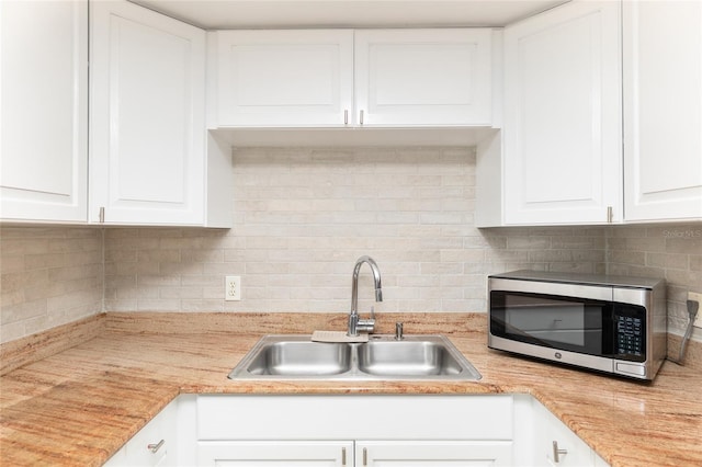 kitchen with sink, white cabinetry, and backsplash