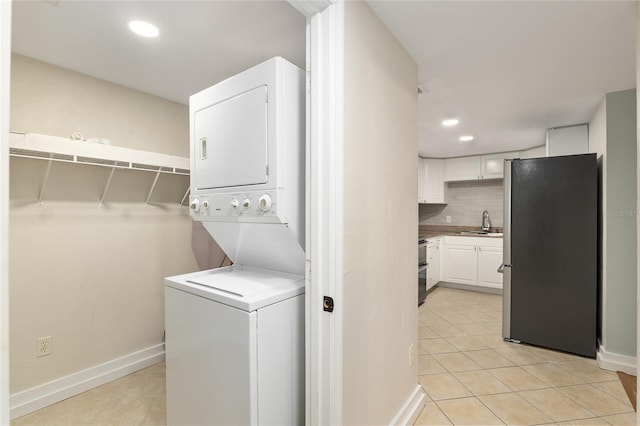 laundry area with stacked washing maching and dryer, sink, and light tile patterned floors