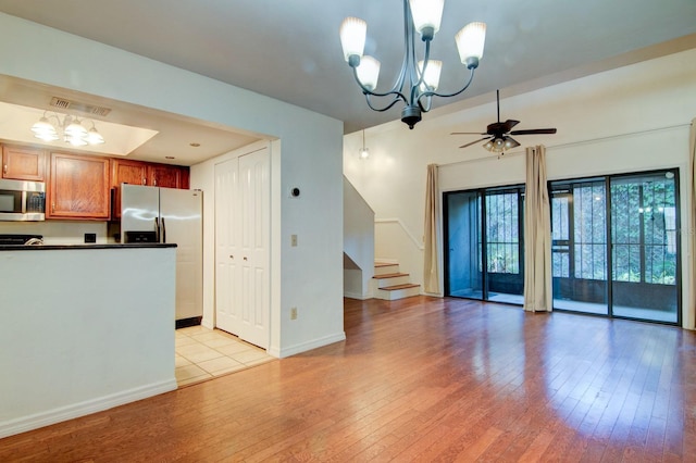 kitchen with pendant lighting, stainless steel appliances, ceiling fan with notable chandelier, and light hardwood / wood-style floors