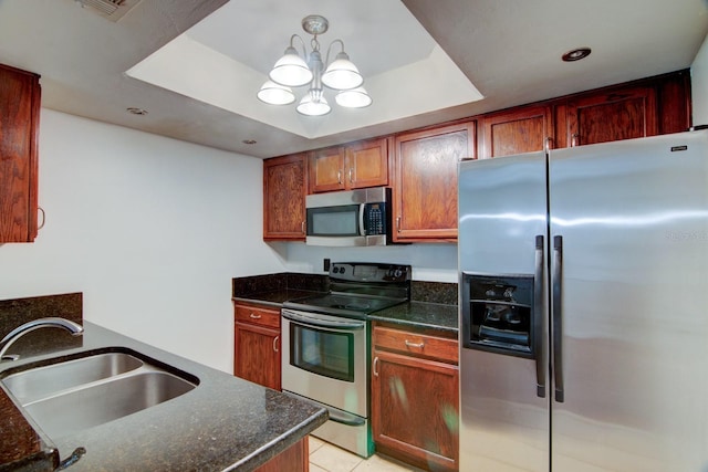 kitchen with sink, dark stone countertops, a chandelier, a tray ceiling, and appliances with stainless steel finishes