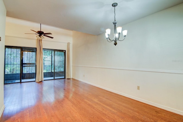 spare room featuring wood-type flooring and ceiling fan with notable chandelier