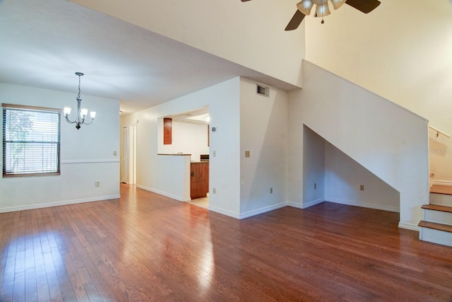 unfurnished living room featuring hardwood / wood-style floors and ceiling fan with notable chandelier