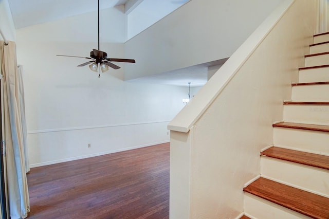 stairway with hardwood / wood-style floors, ceiling fan with notable chandelier, and lofted ceiling