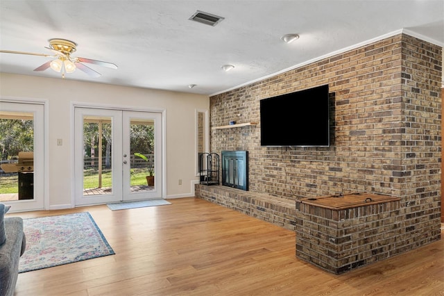 living room featuring french doors, light hardwood / wood-style flooring, ceiling fan, and brick wall