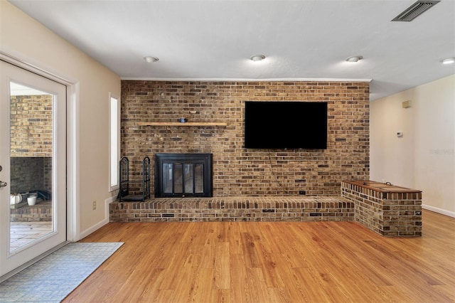 unfurnished living room featuring light wood-type flooring and a brick fireplace