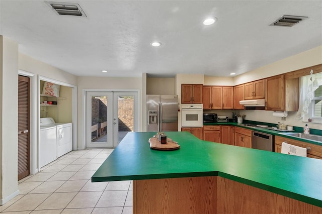 kitchen with french doors, sink, independent washer and dryer, light tile patterned floors, and stainless steel appliances