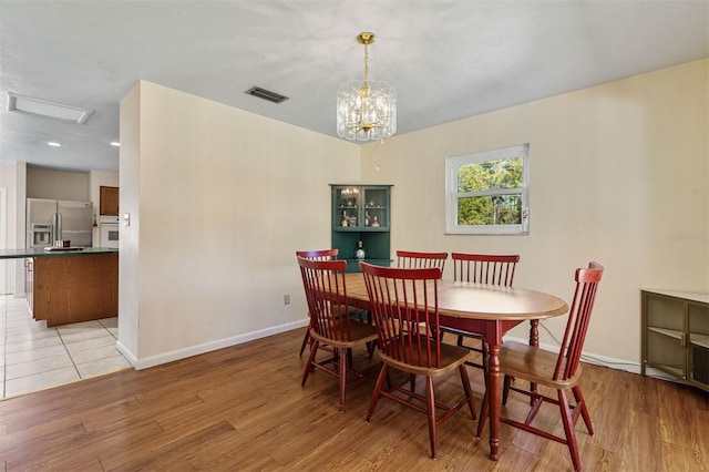 dining space with light hardwood / wood-style flooring and a notable chandelier