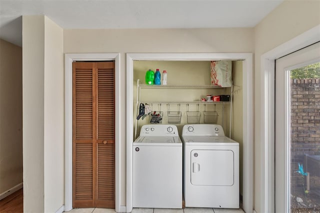 clothes washing area with washer and dryer and light tile patterned floors