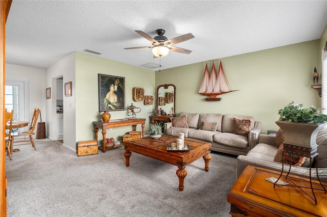 carpeted living room with ceiling fan and a textured ceiling