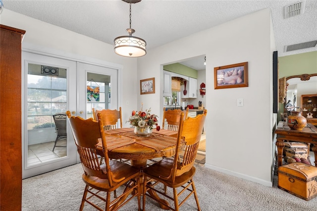 carpeted dining area featuring a healthy amount of sunlight, a textured ceiling, and french doors