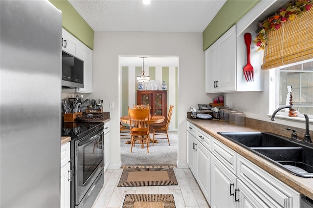 kitchen with white cabinetry, sink, stainless steel appliances, pendant lighting, and a textured ceiling