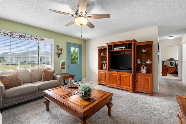 living room featuring ceiling fan, light colored carpet, and a textured ceiling