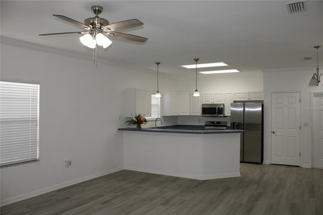 kitchen with kitchen peninsula, ceiling fan with notable chandelier, stainless steel appliances, white cabinetry, and hanging light fixtures