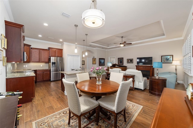 dining area with a tray ceiling, ornamental molding, dark hardwood / wood-style floors, and ceiling fan