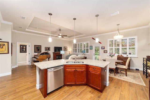 kitchen with sink, dishwasher, a tray ceiling, a center island with sink, and decorative light fixtures