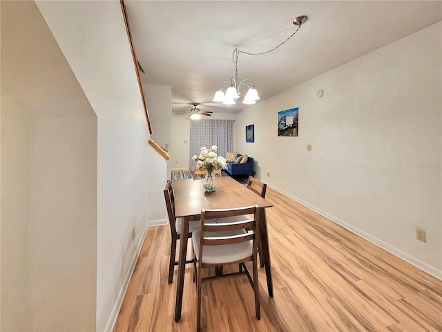 dining space featuring light hardwood / wood-style floors and ceiling fan with notable chandelier