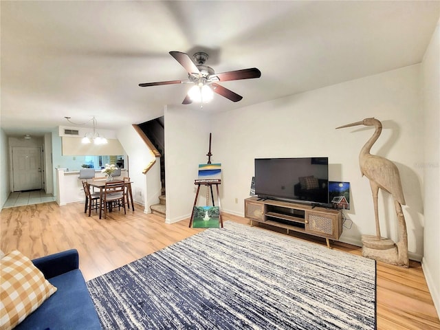 living room featuring ceiling fan with notable chandelier and wood-type flooring