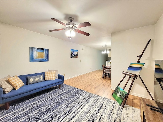 living room featuring ceiling fan with notable chandelier and wood-type flooring