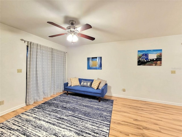 sitting room with ceiling fan and wood-type flooring