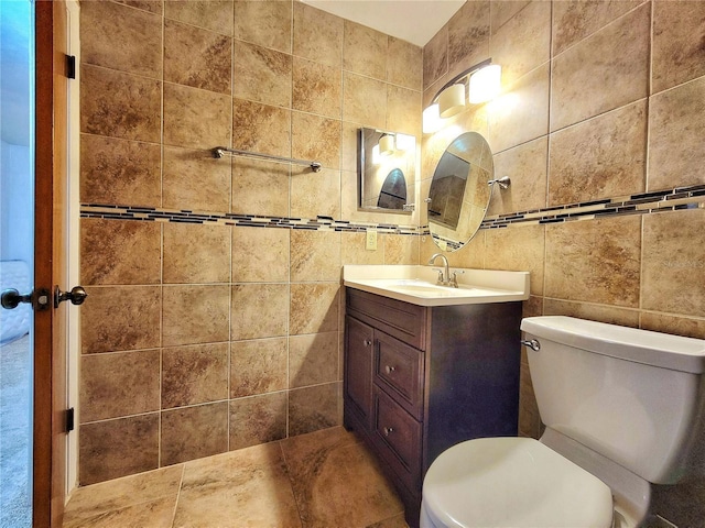 bathroom featuring toilet, vanity, and tile walls