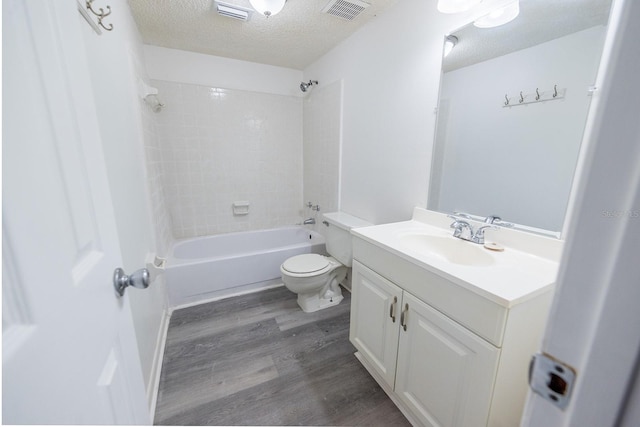 full bathroom with tiled shower / bath combo, hardwood / wood-style floors, a textured ceiling, toilet, and vanity