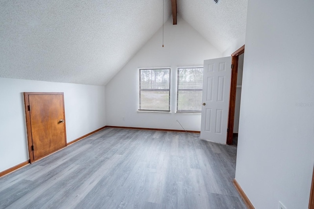 bonus room with lofted ceiling with beams, light hardwood / wood-style floors, and a textured ceiling