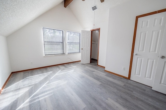 unfurnished bedroom featuring vaulted ceiling with beams, ceiling fan, wood-type flooring, and a textured ceiling