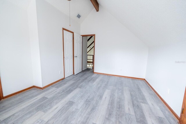 additional living space featuring beamed ceiling, high vaulted ceiling, a textured ceiling, and light wood-type flooring