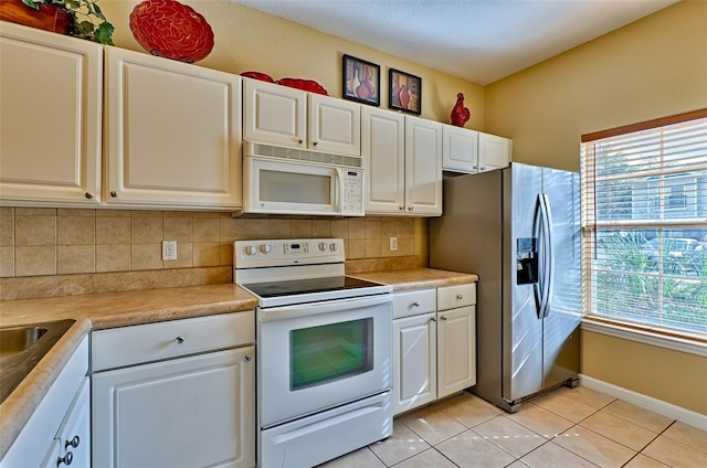 kitchen with tasteful backsplash, white cabinetry, light tile patterned floors, and white appliances