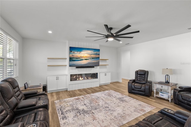 living room with ceiling fan, a fireplace, and light hardwood / wood-style flooring