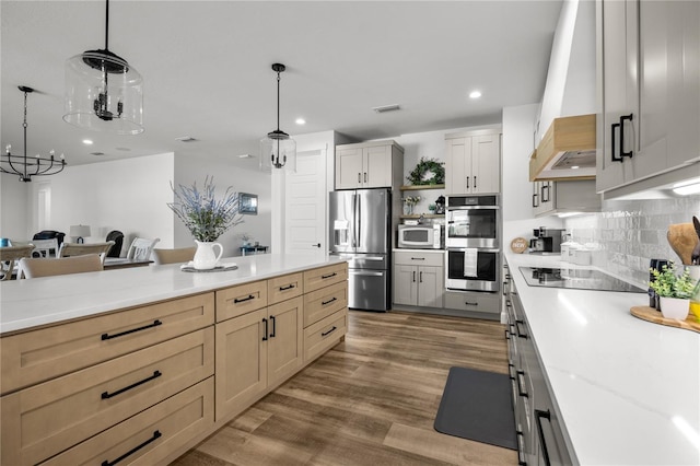 kitchen featuring custom exhaust hood, light brown cabinets, pendant lighting, and appliances with stainless steel finishes